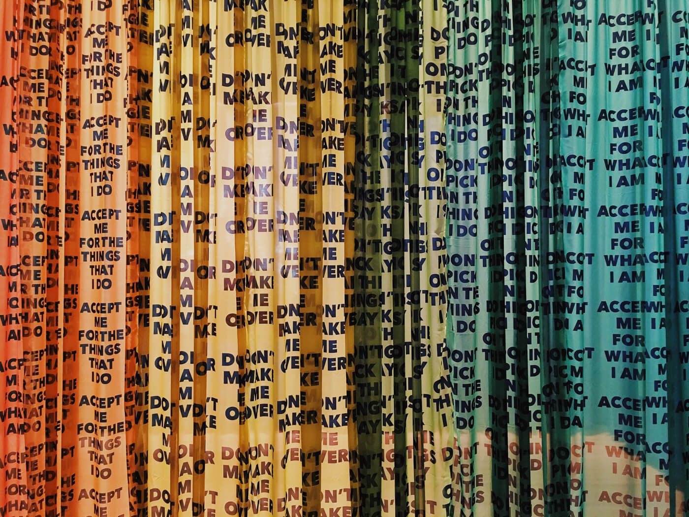 Thin vertical strips hanging with words written on them. The strips form a rainbow