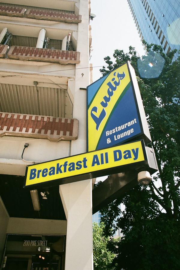 Blue and yellow sign that says Ludi's Restaurant and Lounge and Breakfast All Day.