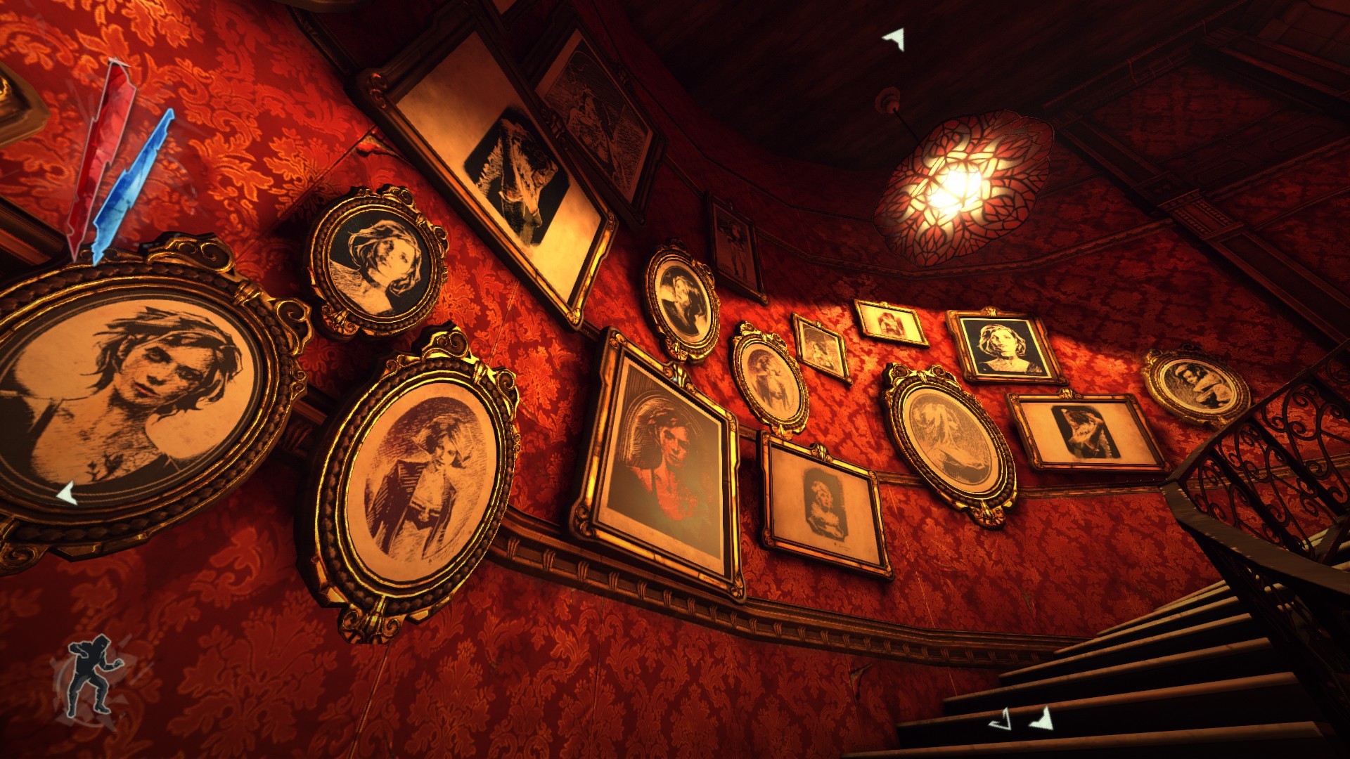 A wall with red wallpaper and filled with portraits.