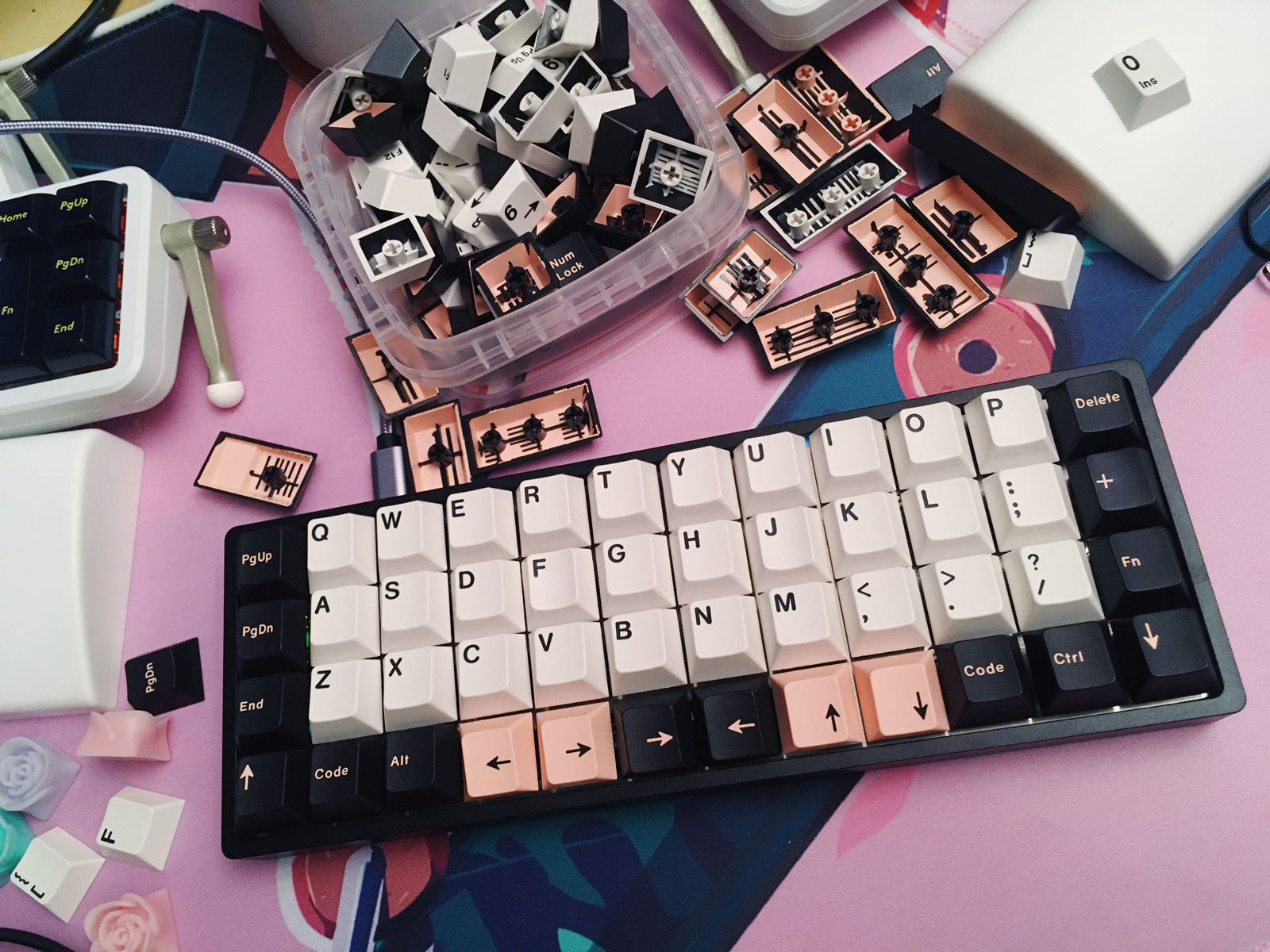 A small black keyboard with white, black, and pink keycaps.