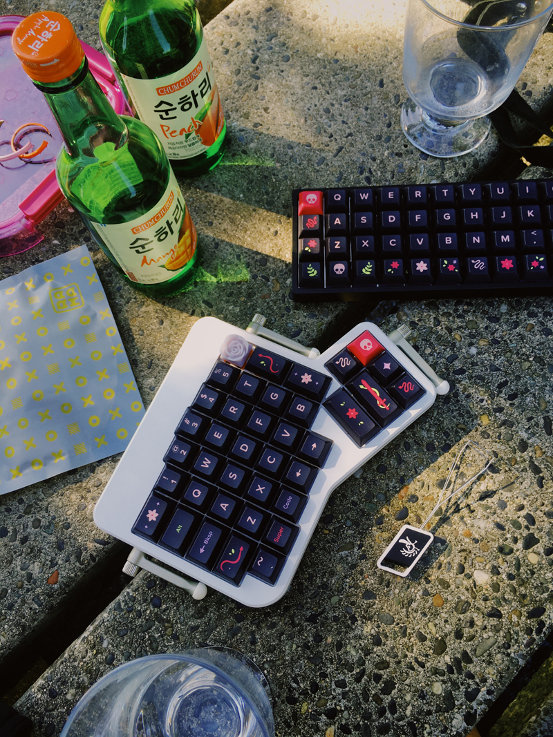 Keyboards and soju on a park table.