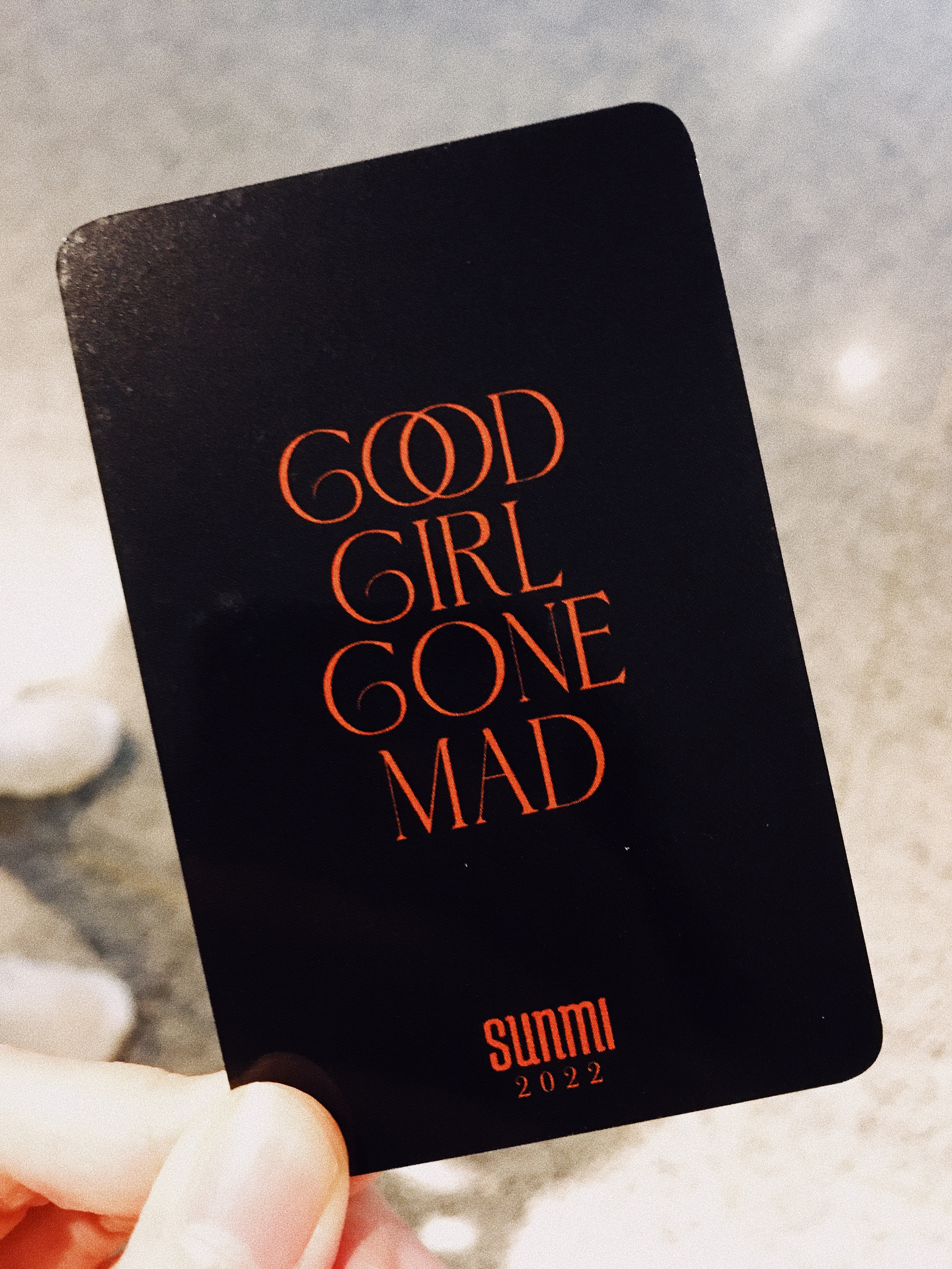Holding a concert photocard that reads 'Good Girl Gone Mad.