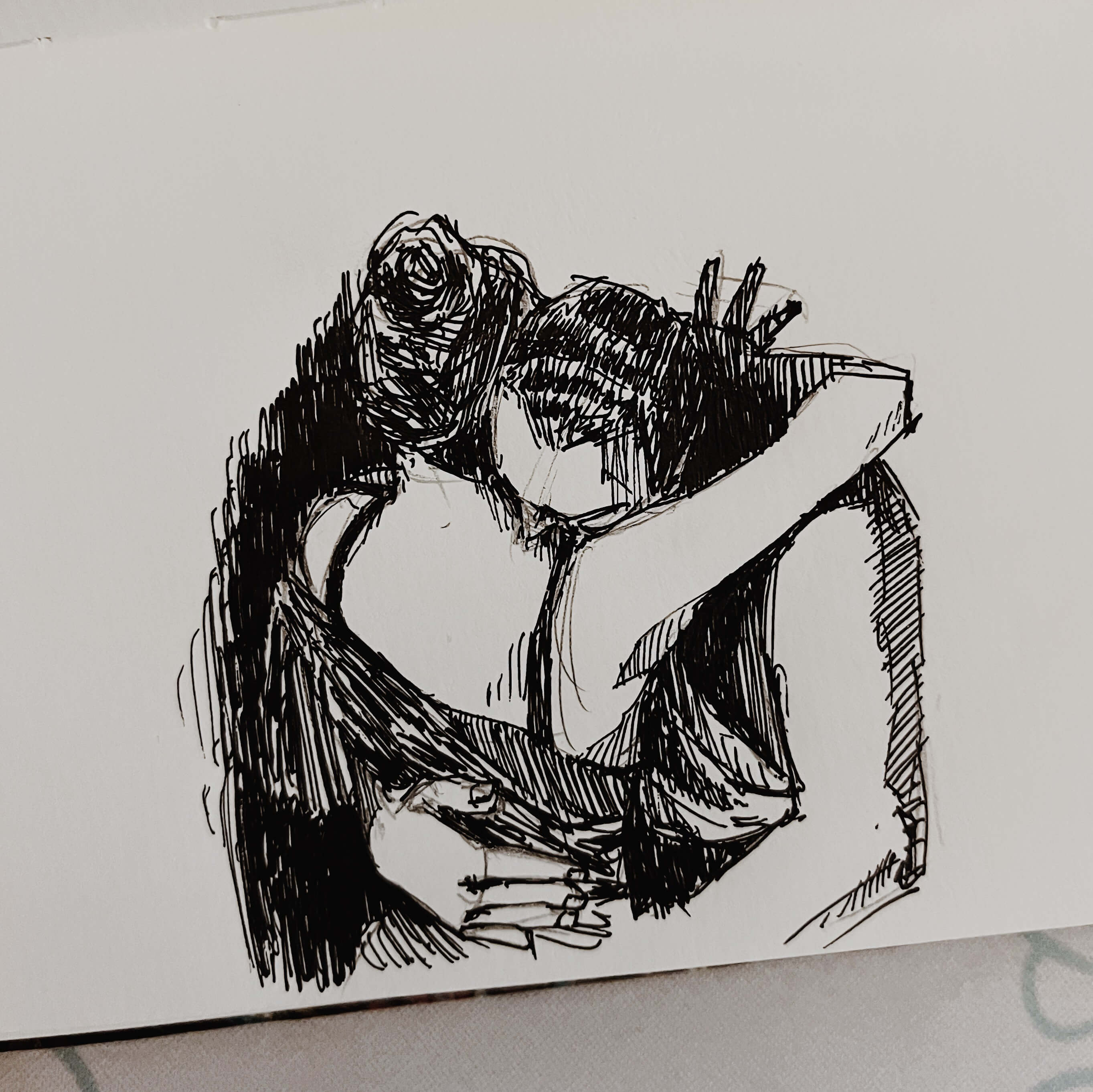 Ink sketch of two dancers embracing during a tango routine. The man has his face pressed into the woman’s shoulder and his hand around her back. 