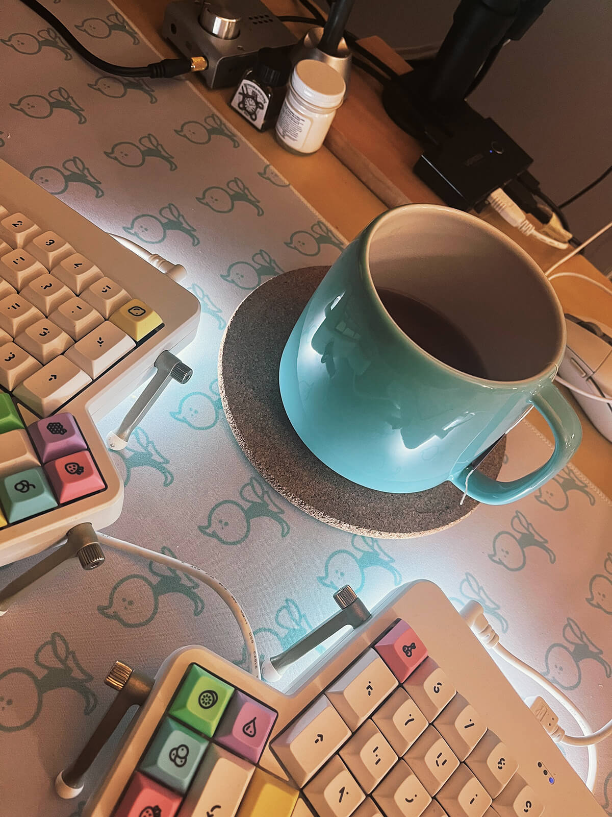 A big mug of tea in between my keyboard on my desk. Lots of messy cables in the background.