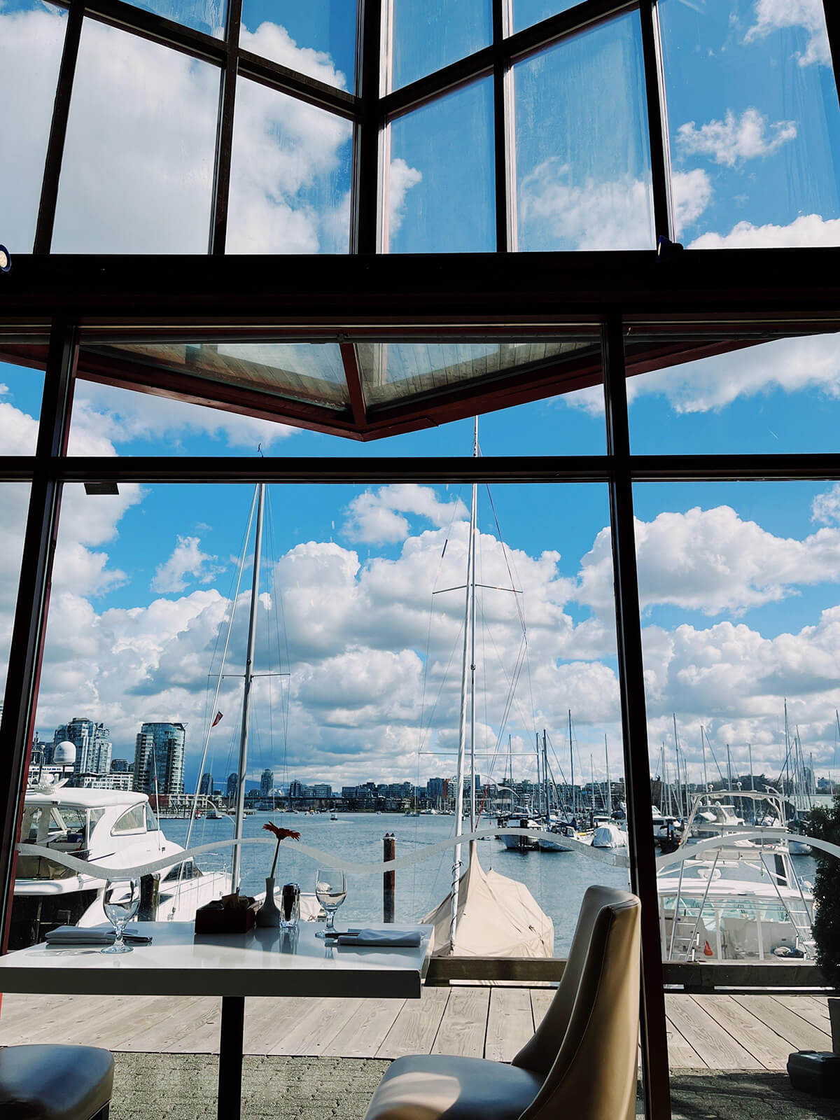 View of boats and a dock outside a restaurant window. There are lots of clouds and a bright blue sky.