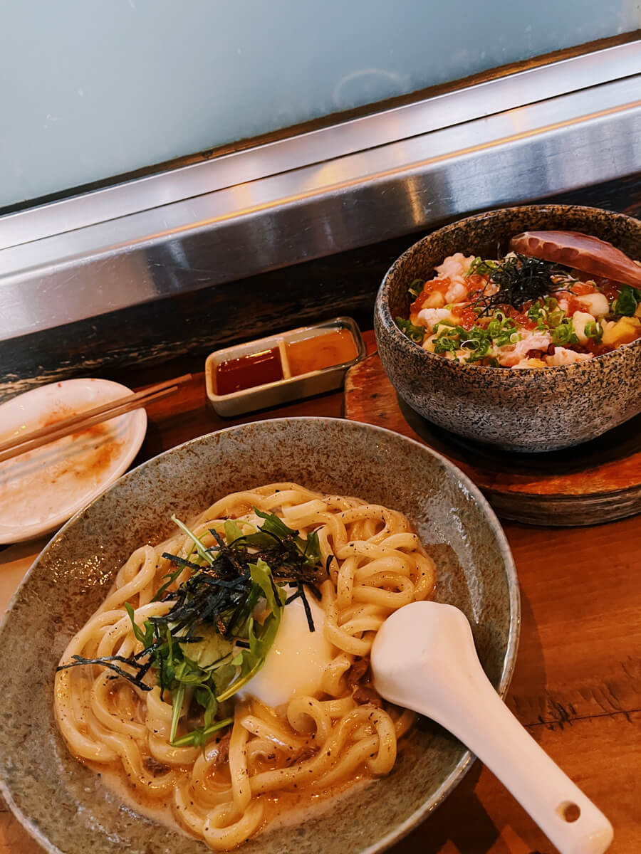A plate of udon with greens and a poached egg, and a bowl of bibimbap.