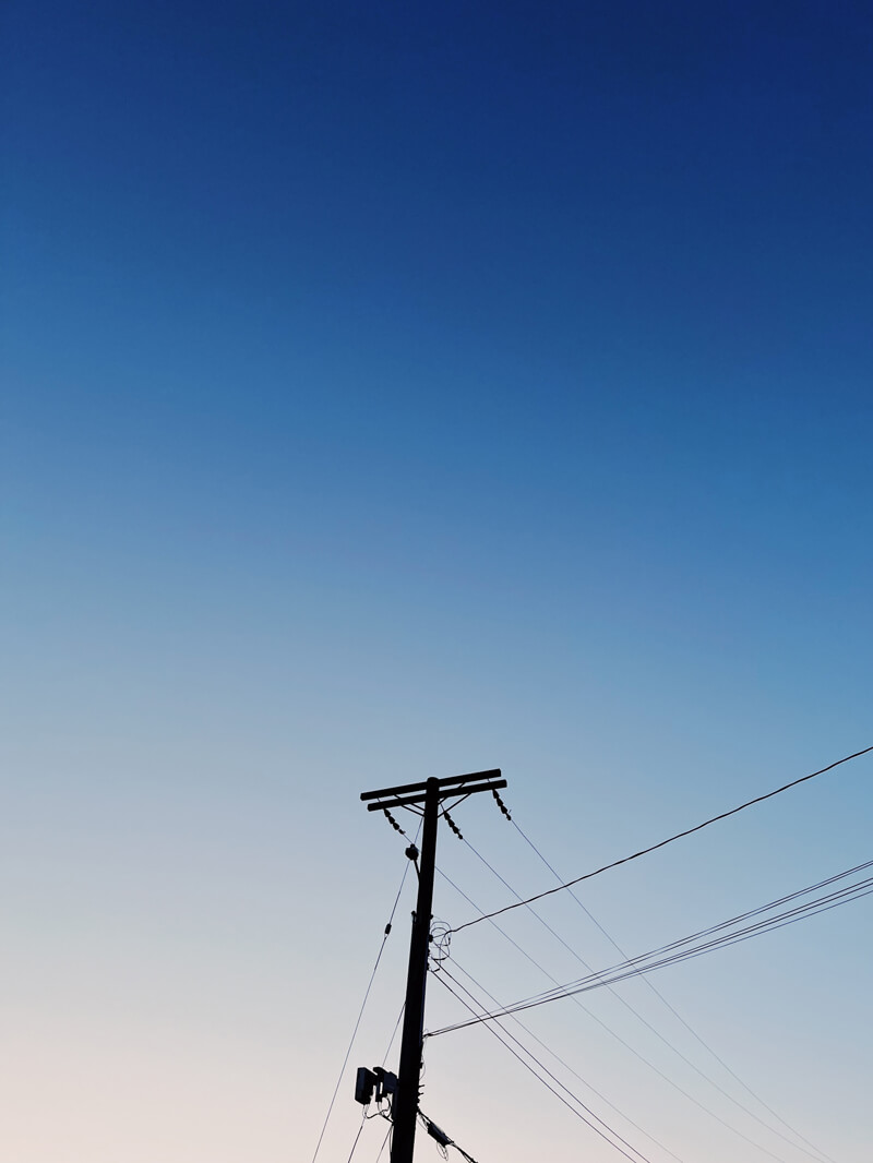 Looking up at a utility pole with power lines extending from it.