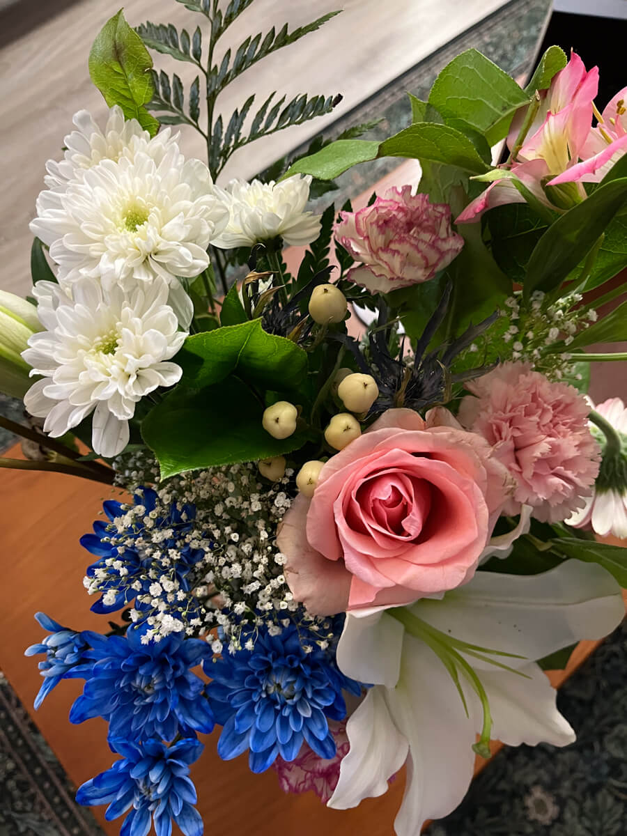 A pretty arrangement of white, pink, and blue flowers, framed by green leaves.