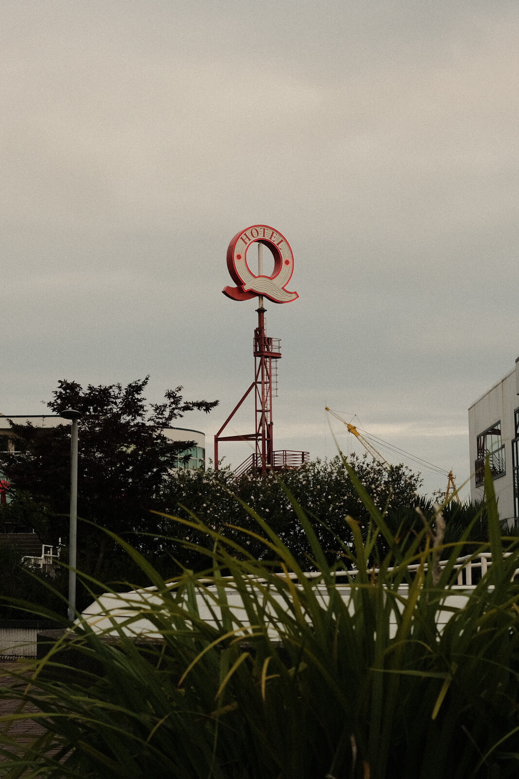  A tall, narrow structure in the distance with a large ‘Q’ at the top and the words ‘hotel,’ under an overcast sky.