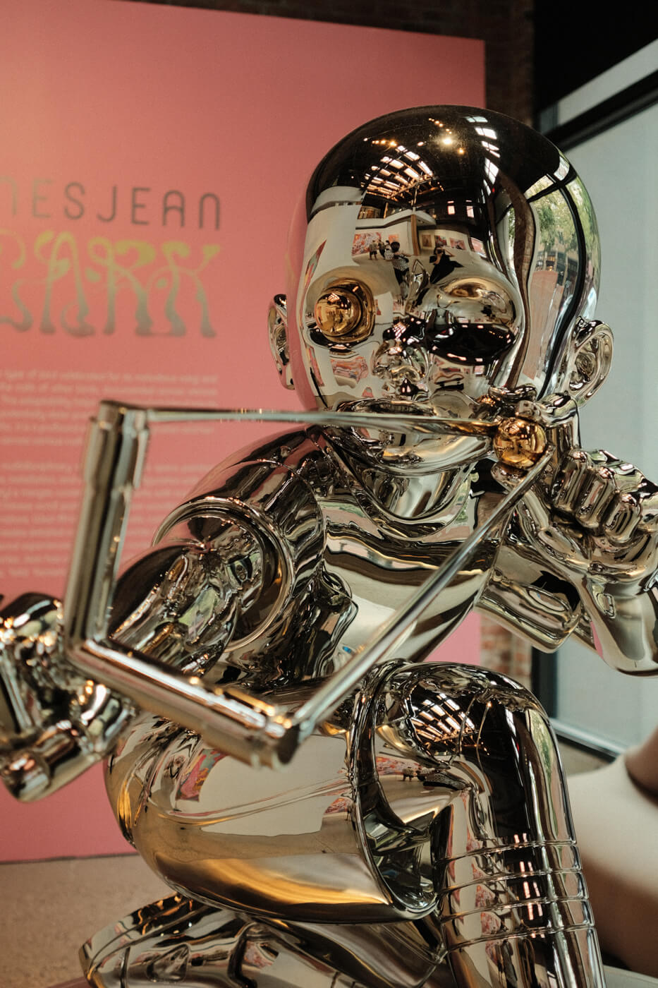 A reflective, metallic sculpture of a boy aiming a slingshot with one golden eyeball.