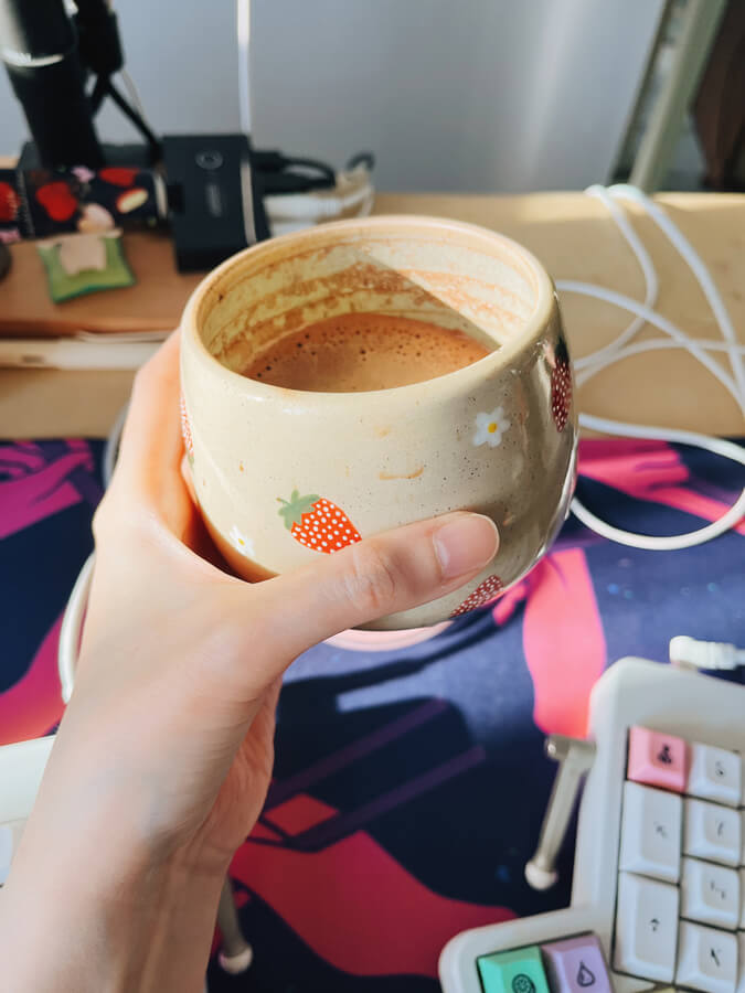 Holding up a mug filled with an espresso drink at my desk.