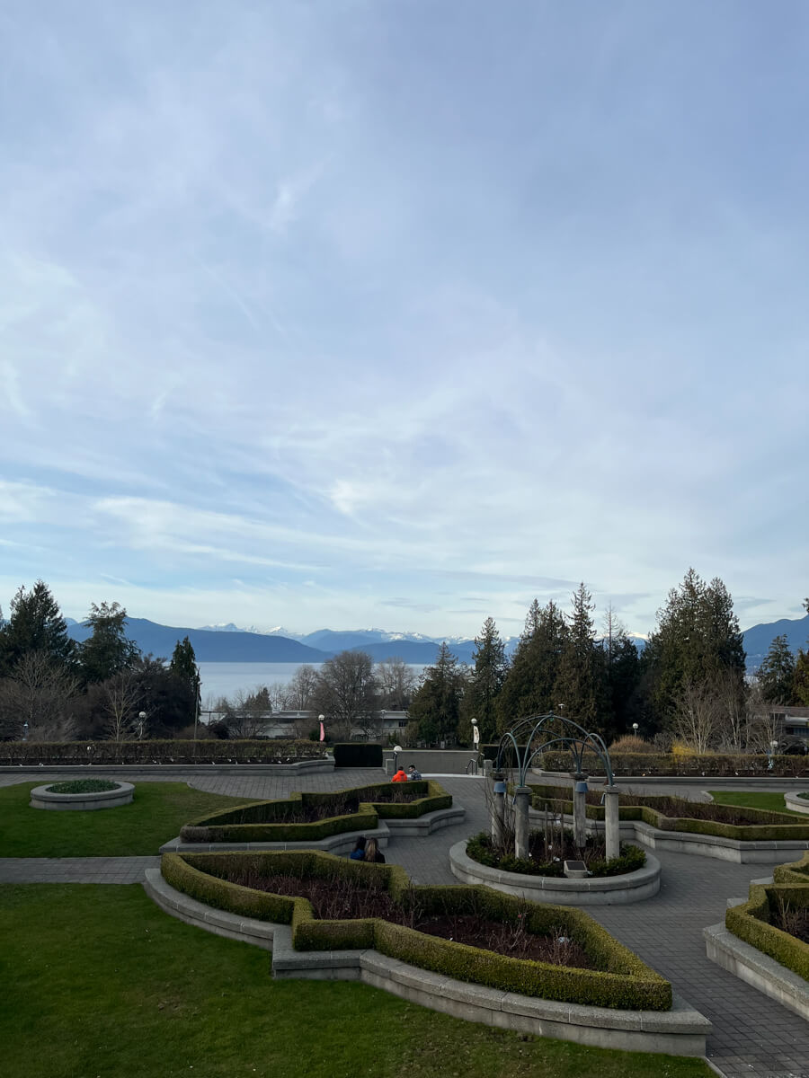 A garden on campus, but devoid of flowers. In the distance is ocean, mountains, and sky.