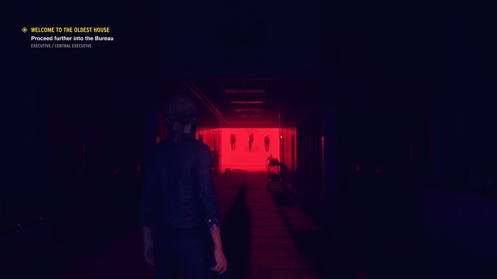 Looking down a dark hallway, where there are 3 floating bodies at the end of it, bathed in vivid red light.