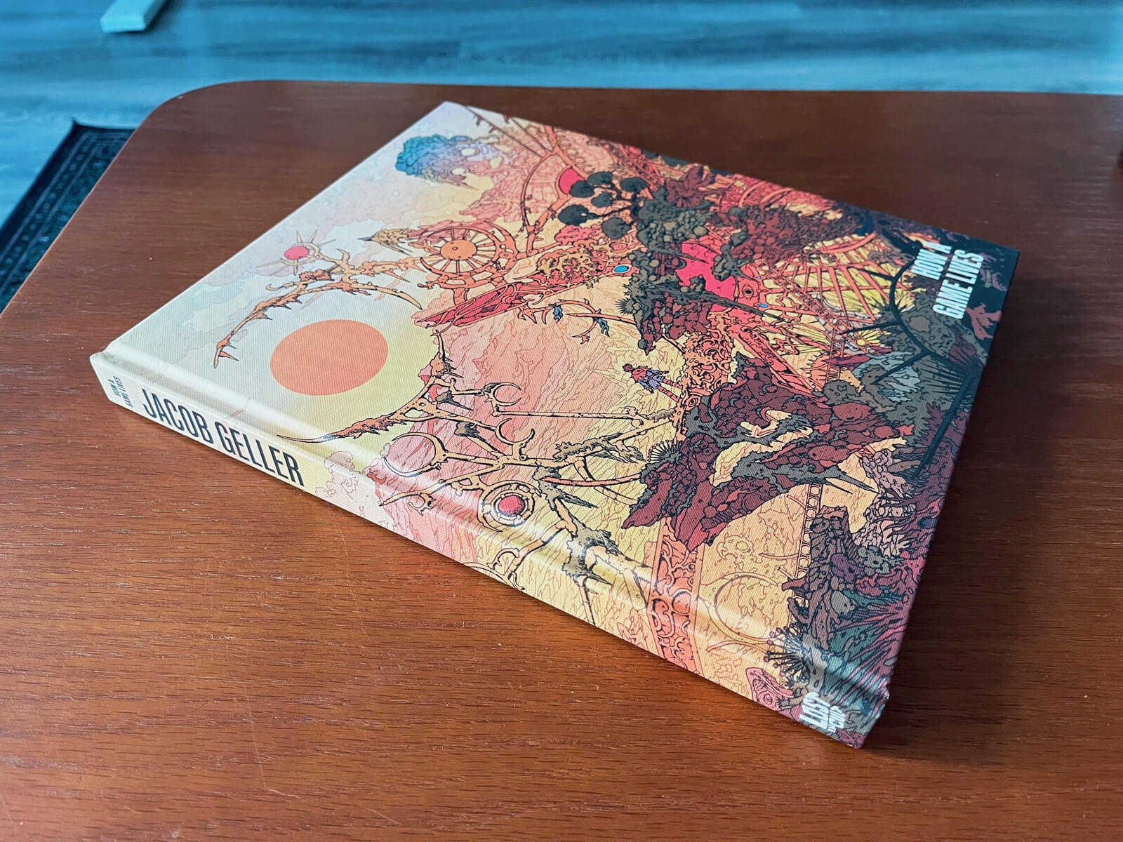 A coffee table book with an intricate illustration of a fantastical, perhaps post-apocalyptic landscape—rubble and ruin, overtaken by greenery—wrapping around the cover.