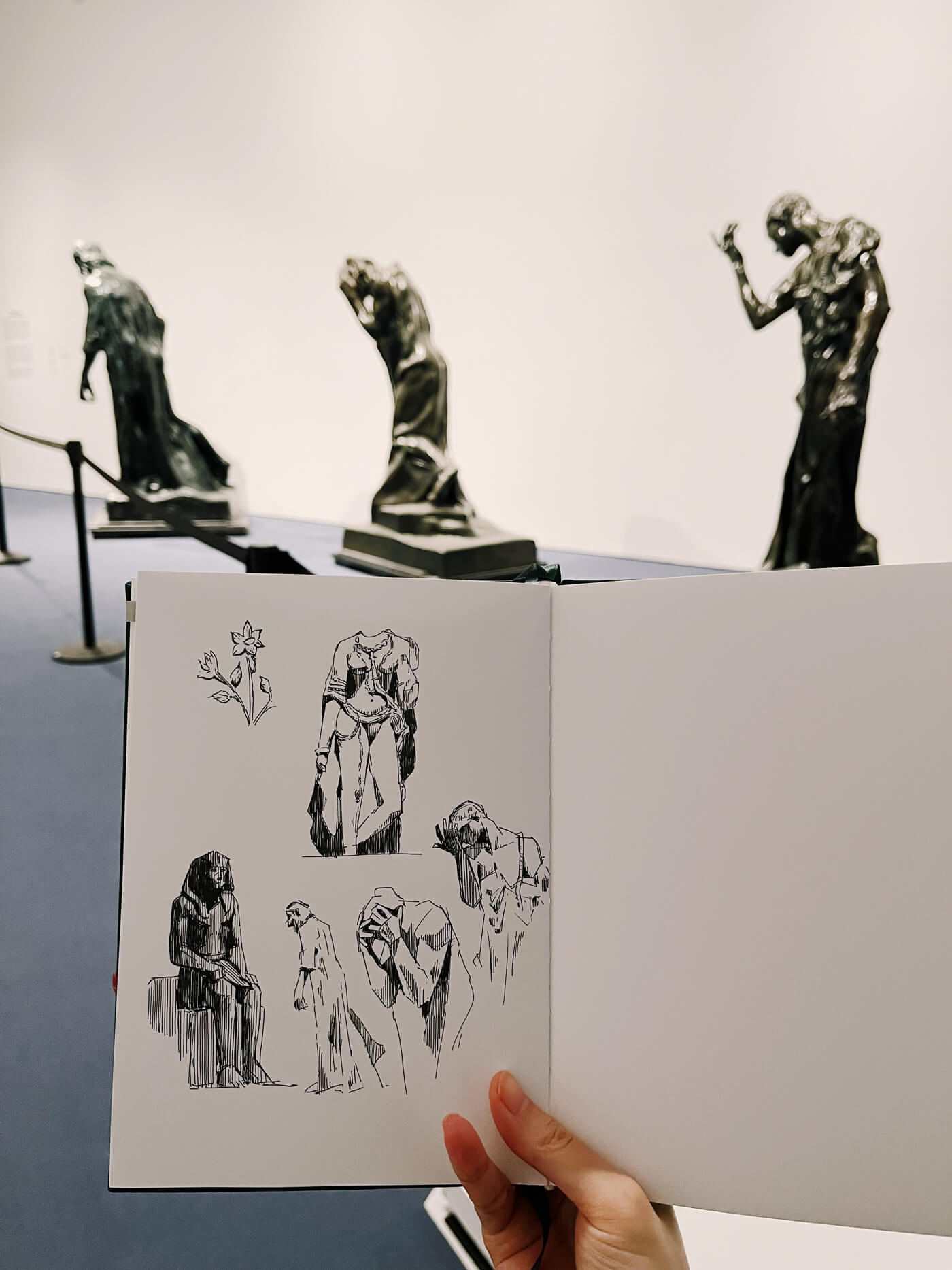 Sketchbook in front of three Rodin sculptures.