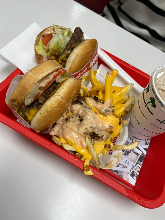 Two burgers and fries drenched in what appears to be cheese and sauce.