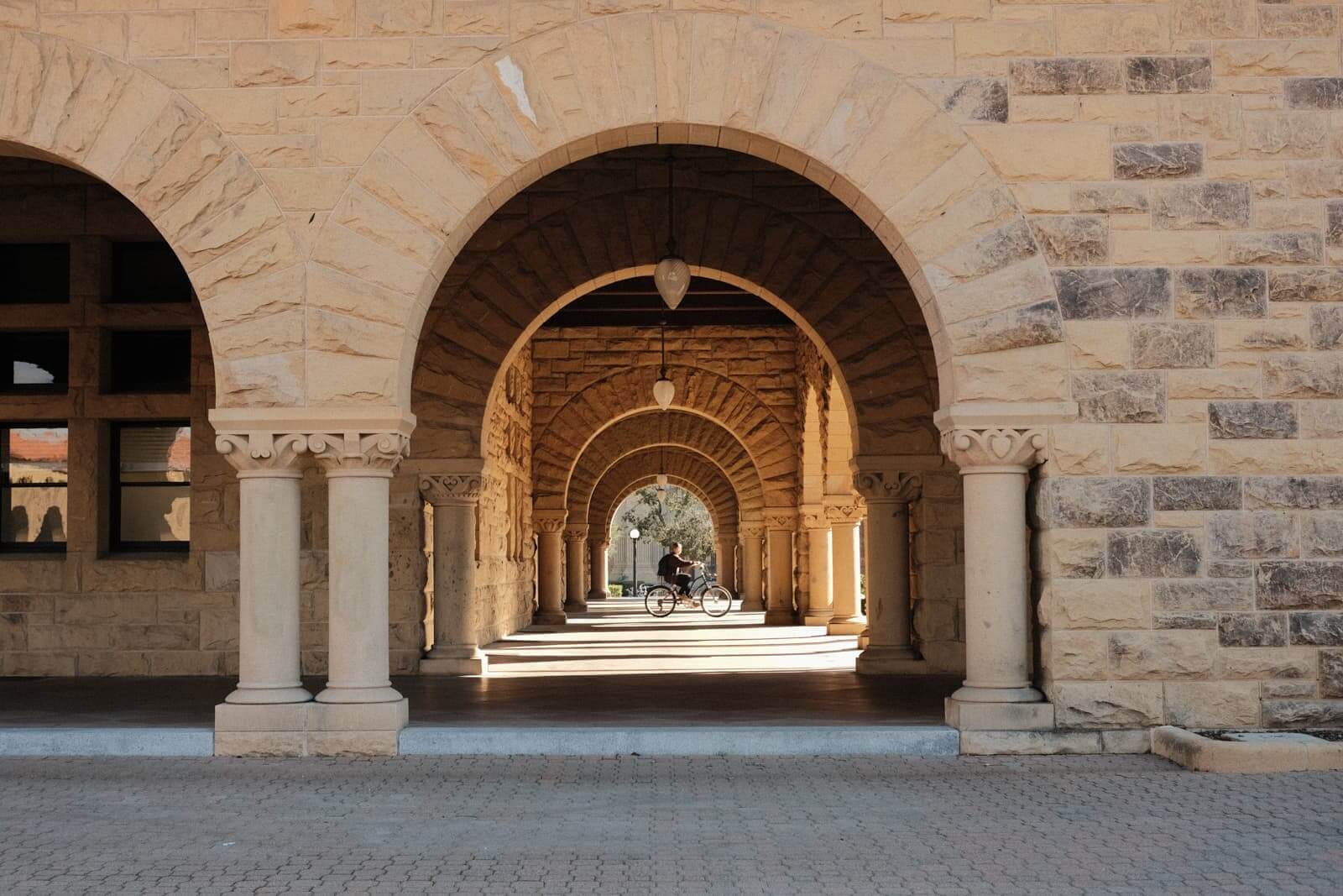 Looking down another covered walkway, where a biker rides through, framed by the round arch.