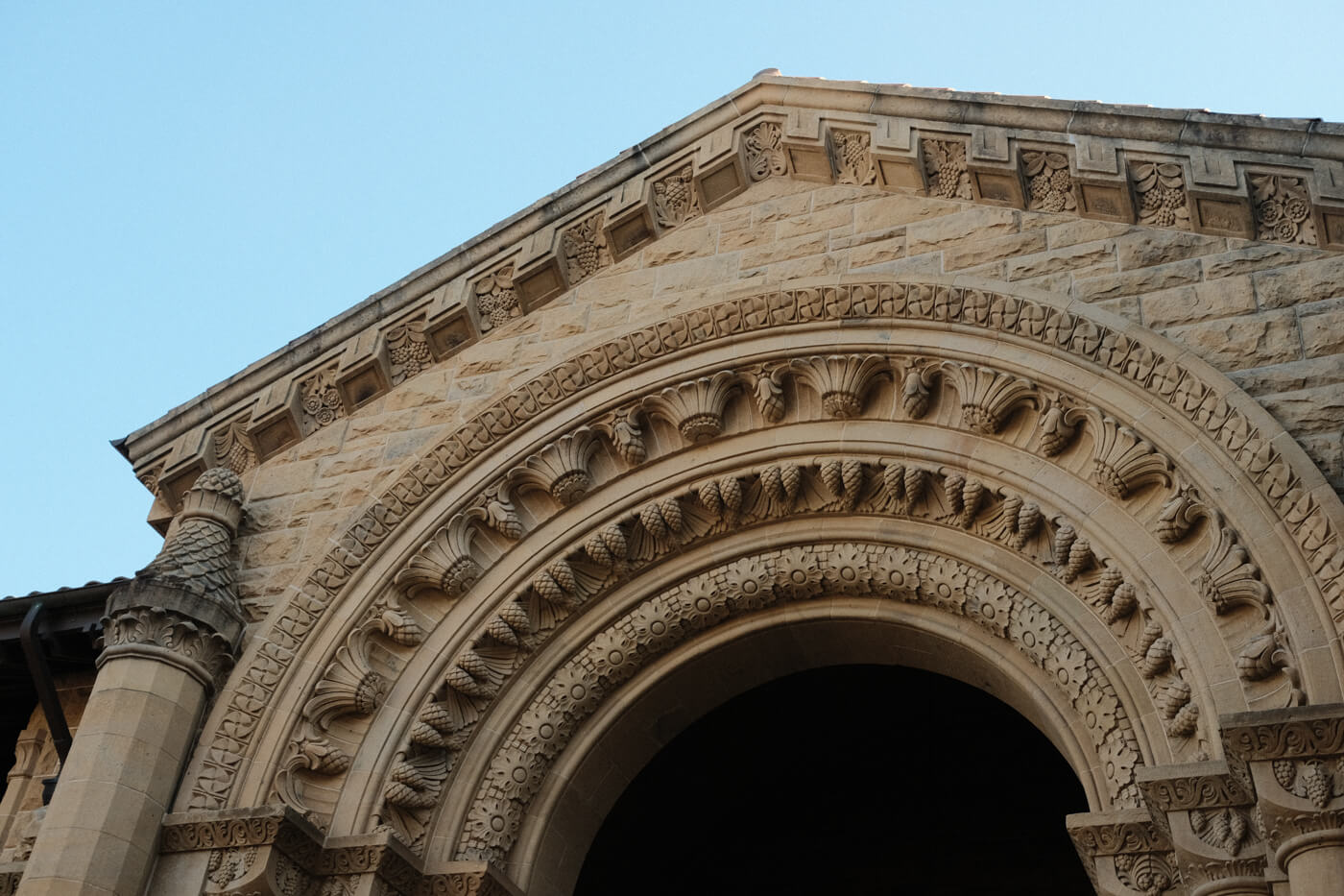 The top of a building. The arch and pointed roof have intricate sculpted borders.