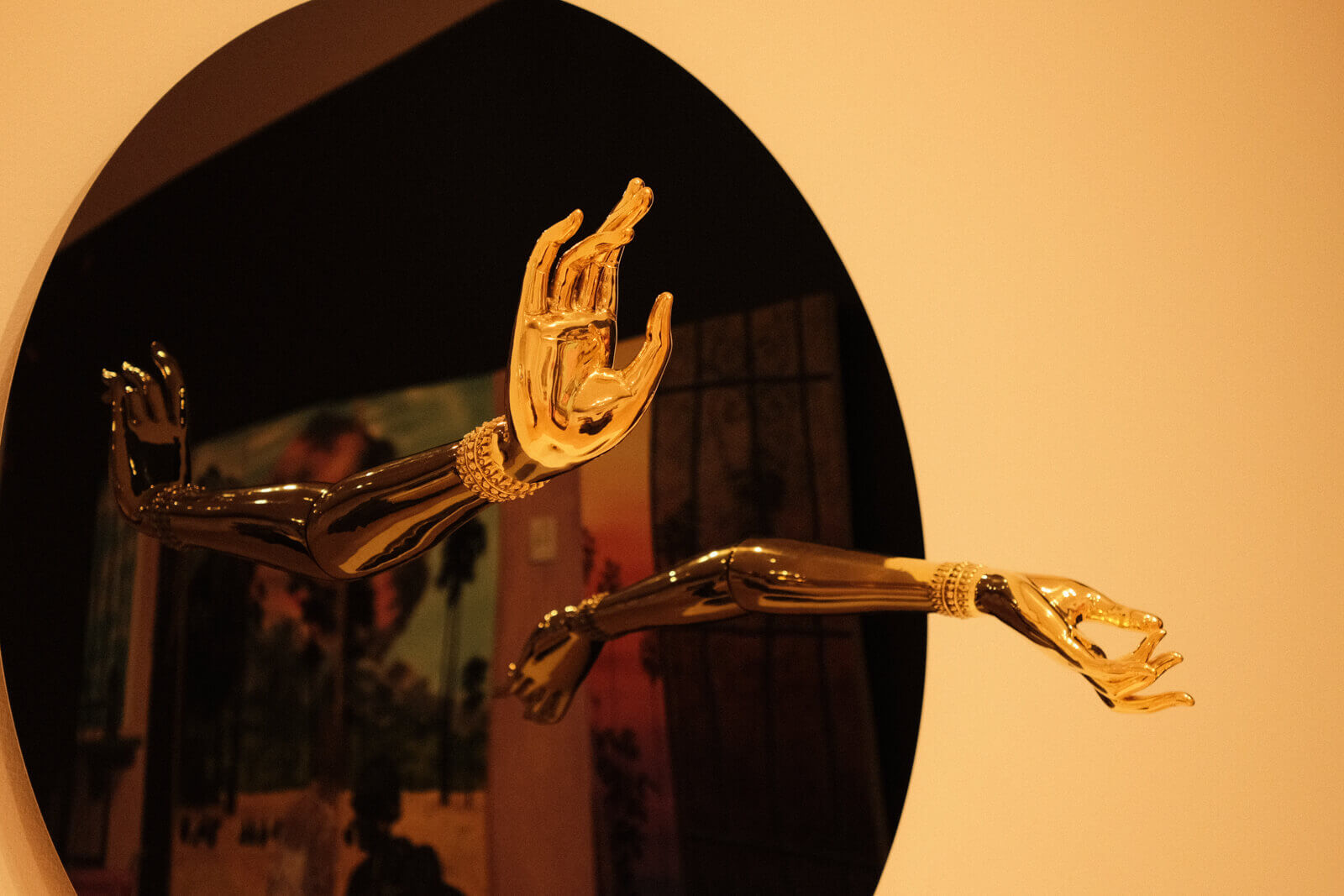 Two sculpted hands made of brass, set on a large black disc.