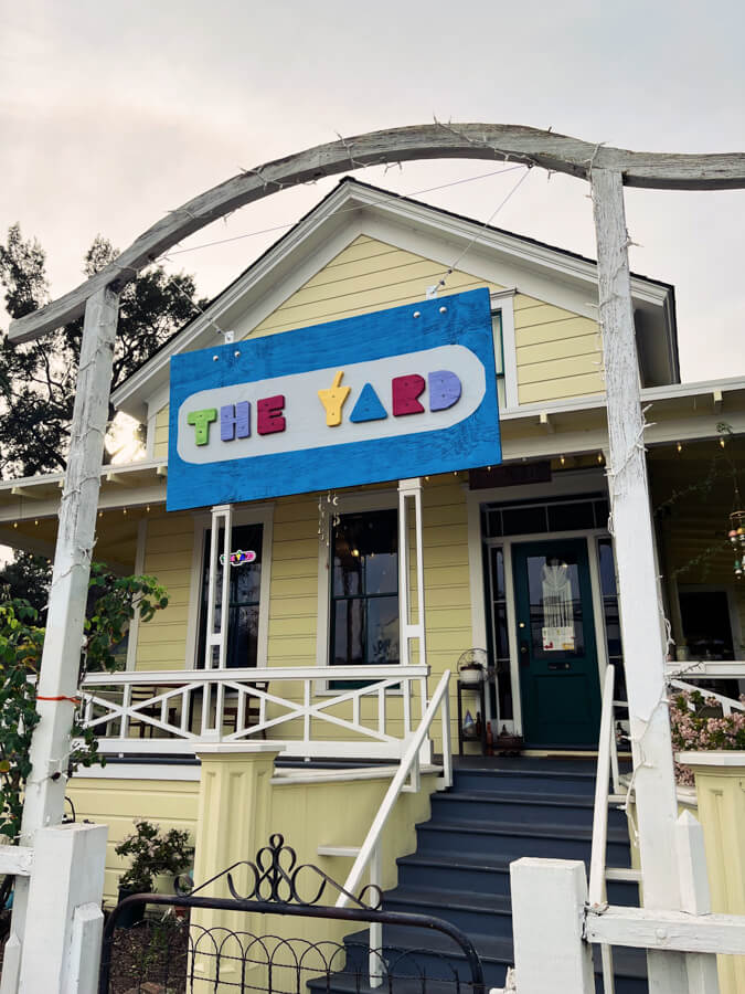 A yellow house with a colourful sign labeling it ‘The Yard.’