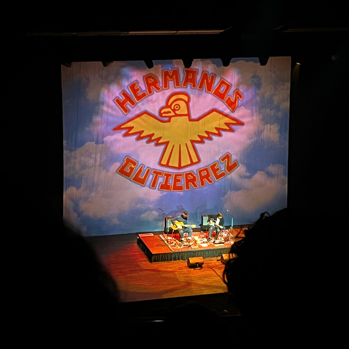 An intimate concert stage with two men playing guitar.